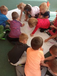 Dzieci z grupy II "Kotki" codziennie wspólnie i radośnie się bawią. Dzisiaj utrwalały części ciała i kolorowały ubranie postaci na dużym arkuszu papieru. 