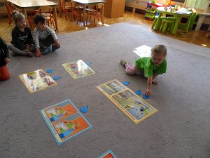 Dzieci siedzą na dywanie przed planszami z dopasowanymi wszystkimi kropelkami.