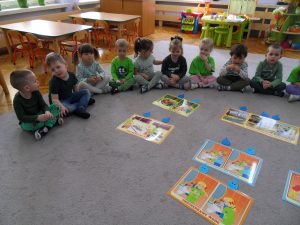 Dzieci siedzą na dywanie przed planszami z dopasowanymi wszystkimi kropelkami.