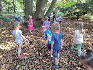 Dzieci w parku zbierają kasztany.