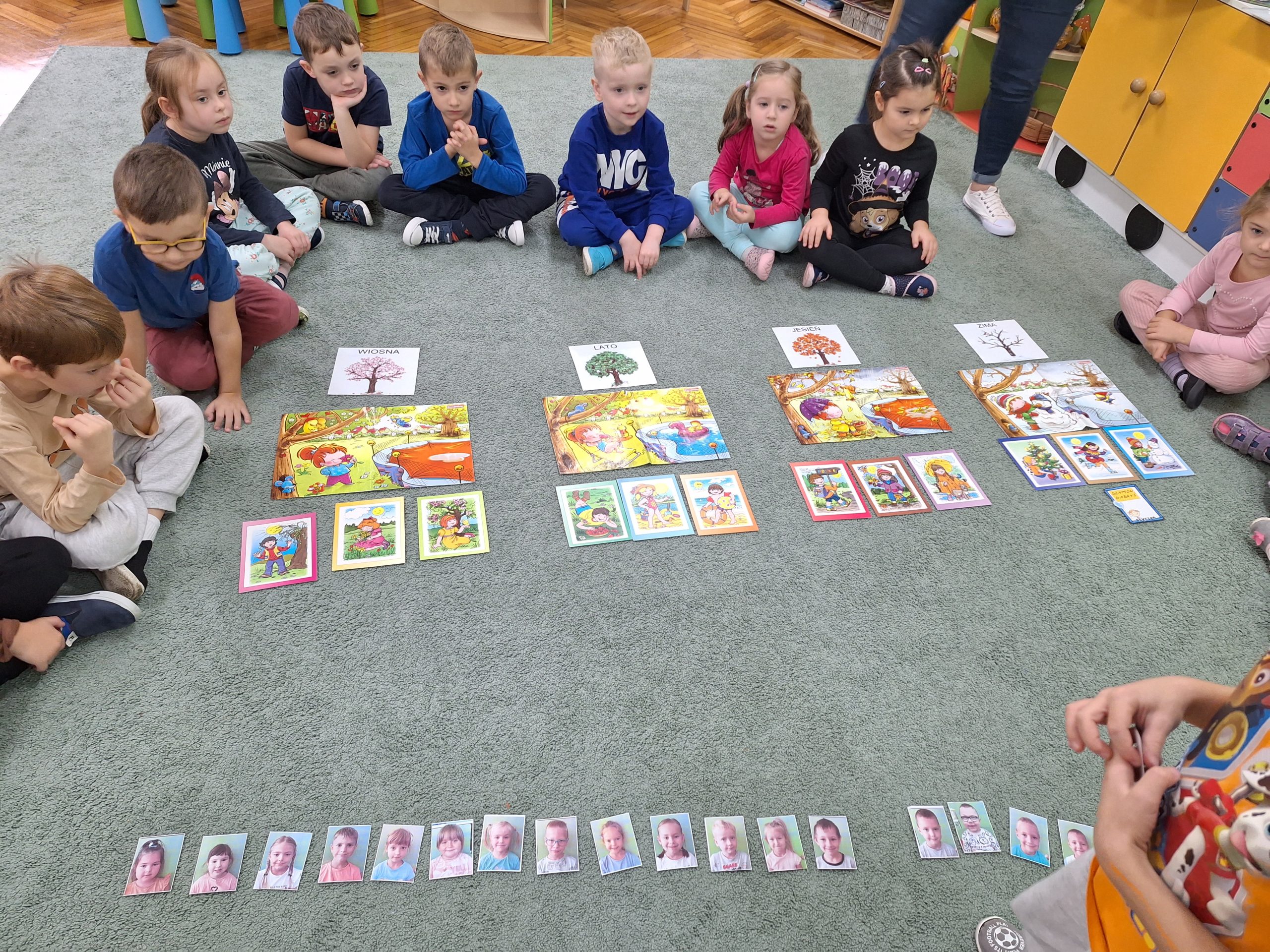 Dzieci siedzą wokół ilustracji z porami roku.