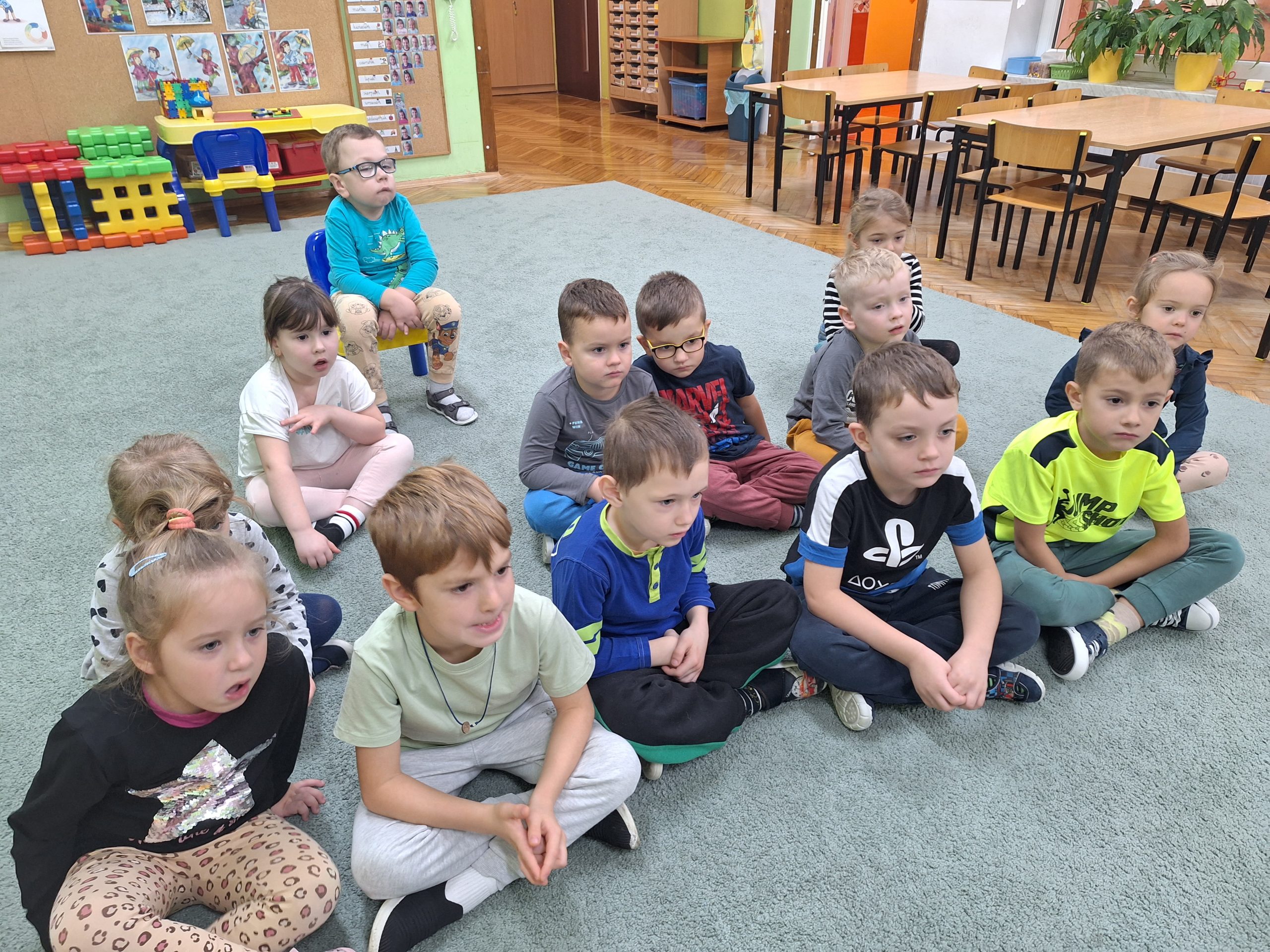 Dzieci z grupy kotków siedzą na dywanie