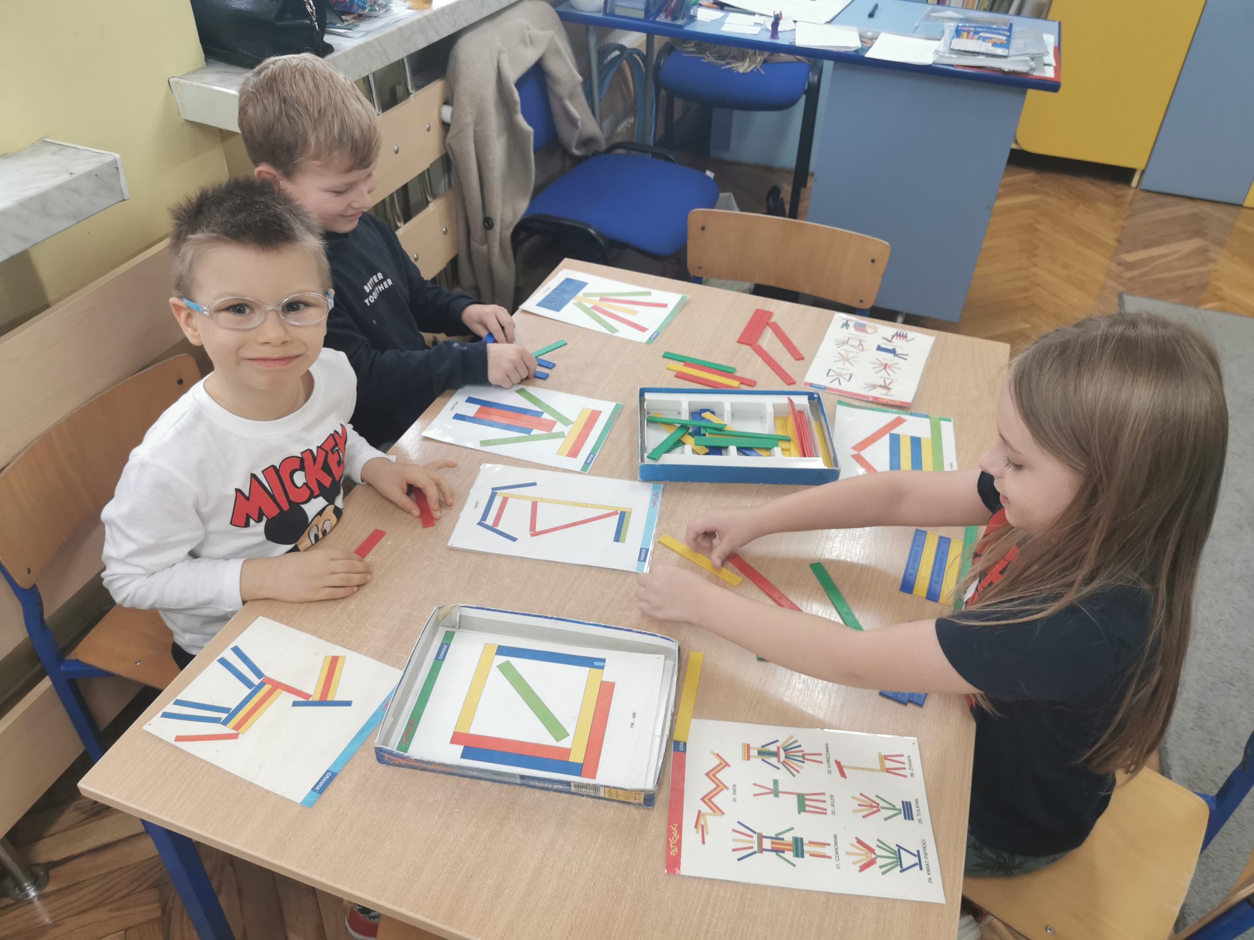 Zabawy Patyczakami - chłopcy układają z kolorowych patyczków wzór z wylosowanej planszy