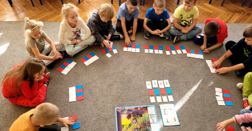 Dzieci układają z nakrywek wyraz tata.