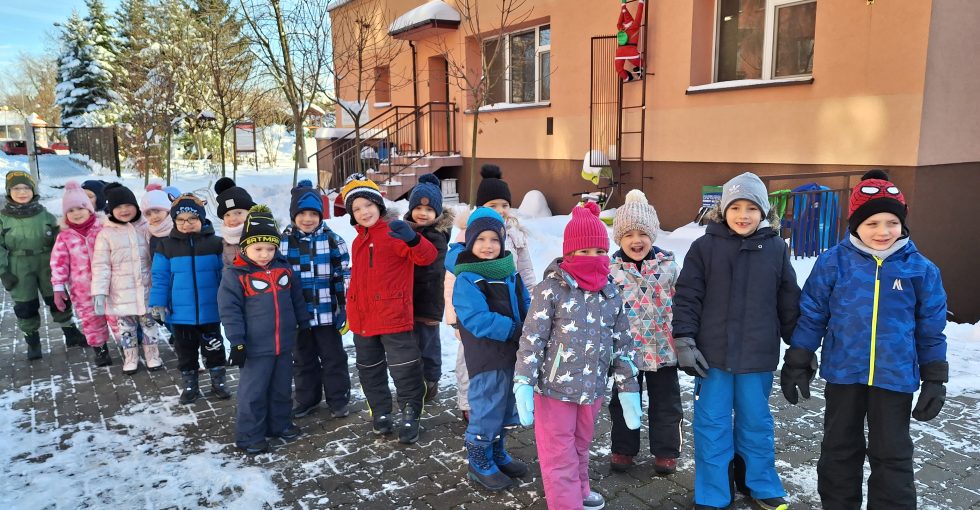 Dzieci z grupy IV pozują do wspólnego zdjęcia przed budynkiem przedszkola.
