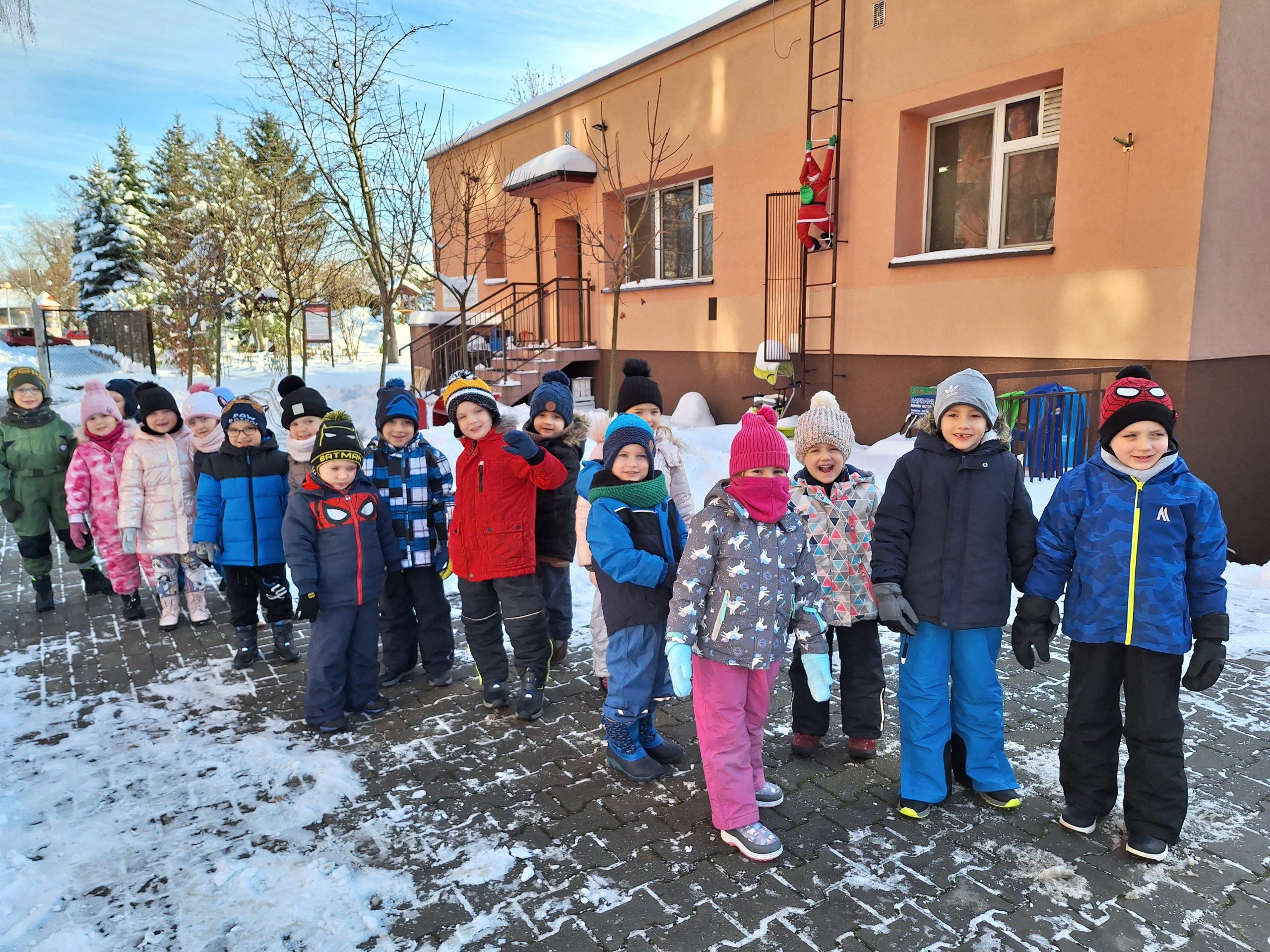 Dzieci z grupy IV pozują do wspólnego zdjęcia przed budynkiem przedszkola.