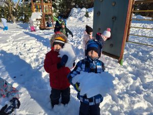 Dwójka chłopców pozuje do zdjęcia z ogromnymi śnieżkami.