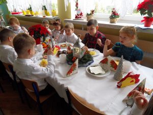 Dzieci siedzą przy stole i jedzą wigilijne potrawy.