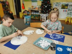 Dzieci za pomocą szablonów odbijają śnieżynki na dwa sposoby: malując pędzlem i białą farbą lub stemplując                    gąbką. Wdrażanie do starannego wykonania pracy.