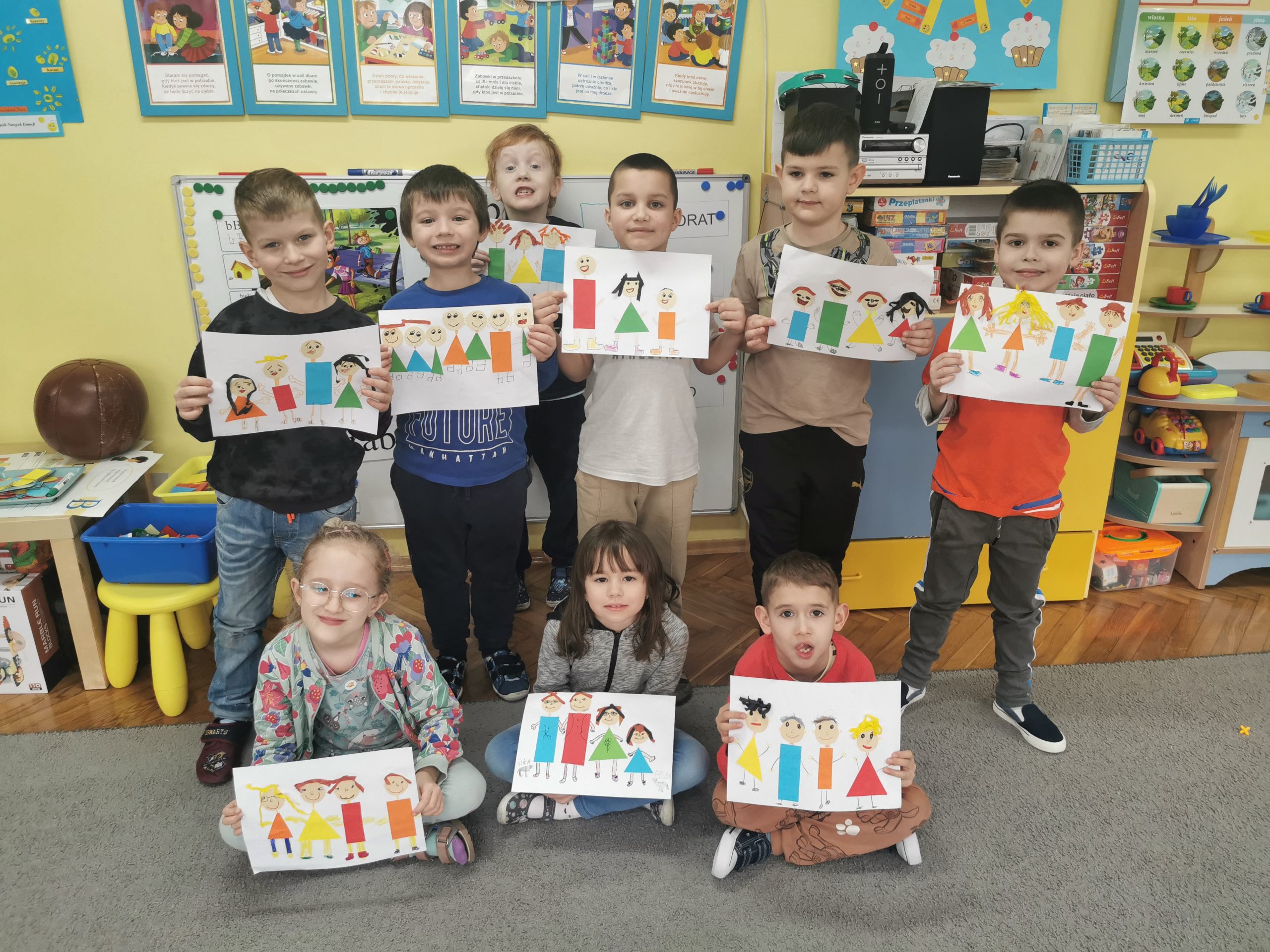 Dzieci pozują do wspólnego zdjęcia prezentując swoje prace.