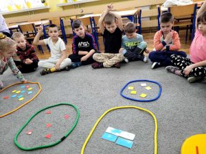 Dzieci klasyfikują figury w kolorowych pętlach