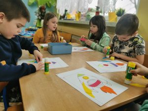 Dzieci wyklejają rakietę kosmiczną kolorowym papierem