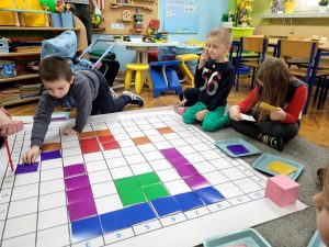 Chłopiec kładzie kwadrat na wskazanym polu, rozpoznając literę i cyfrę.