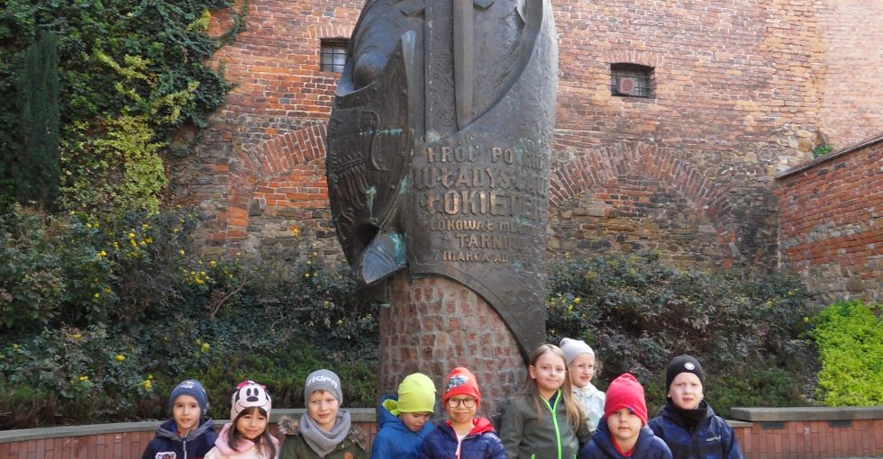 Dzieci stoją przed Pomnikiem Króla Władysława Łokietka .