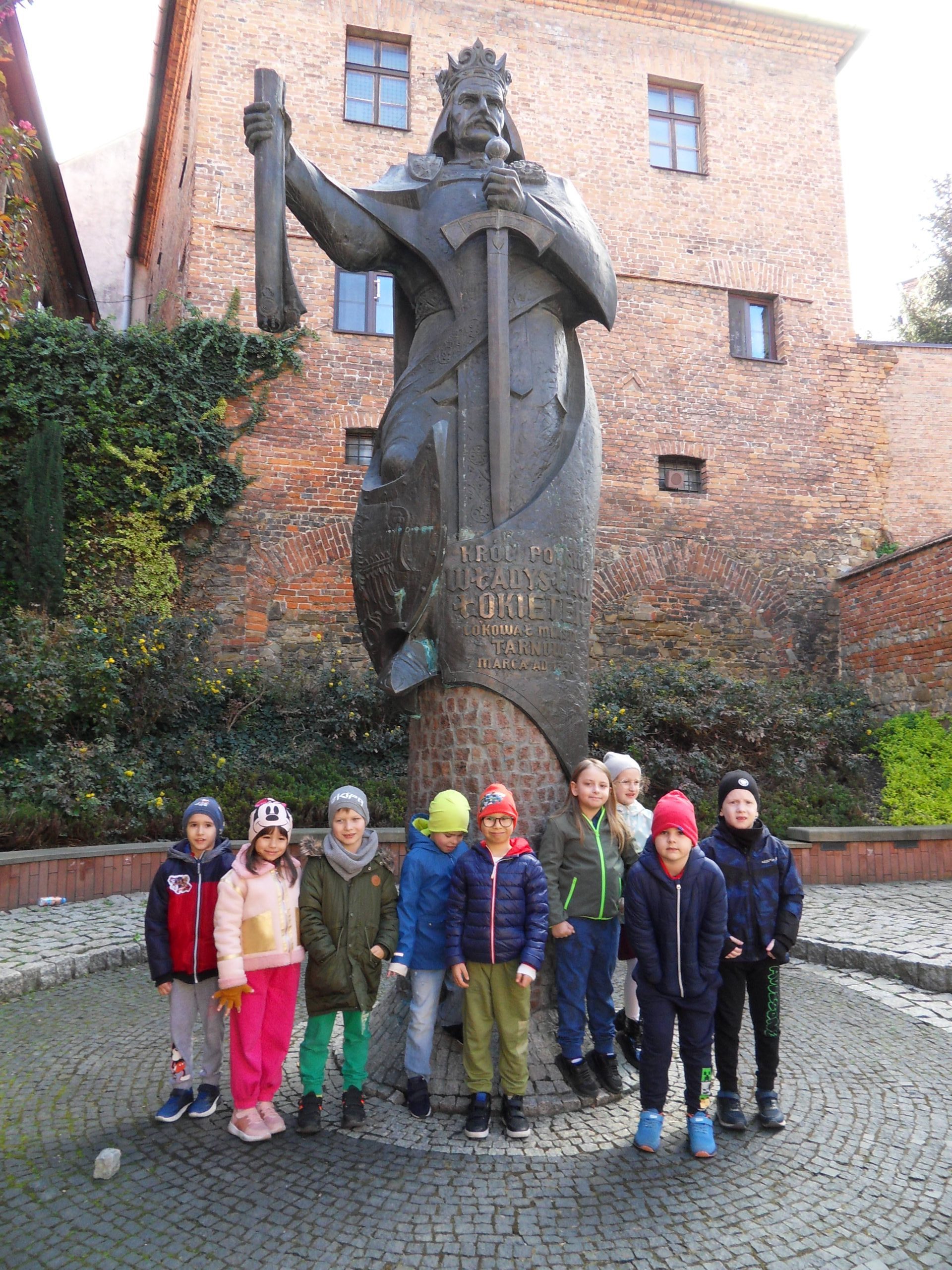Dzieci stoją przed Pomnikiem Króla Władysława Łokietka .