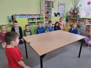 Chłopiec dmucha pompon, który ma toczyć się po stole.