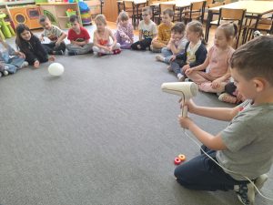 Chłopiec dmucha suszarką w balon.
