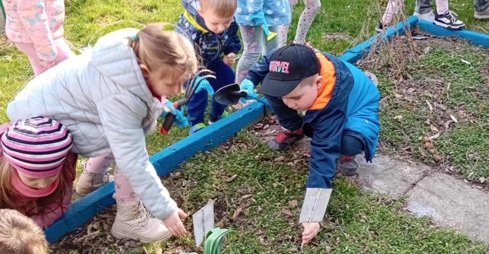 Chłopiec i dziewczynka usuwają zeszłoroczne tabliczki z nazwami roślin z ziemi.