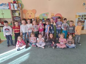 Dzieci z grupy drugiej pozują do zdjęcia z okazji Dnia Kobiet. Dziewczynki trzymają w rękach upominki.