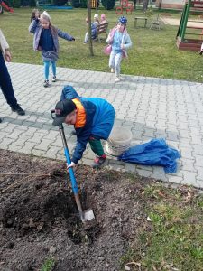 Chłopiec kopie łopatą dołek w ziemi.