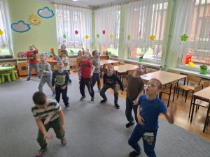 Grupa chłopców dmucha w piórka próbując je utrzymać w powietrzu.