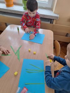 Dzieci naklejają zielone paski papieru - łodygi.