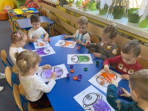 dzieci malują farbami wydrukowane na kartkach garnki