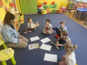 dzieci na dywanie odkrywają obrazki , na których są elementy związane z przyjściem wiosny