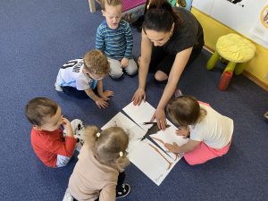 dzieci wraz z nauczycielką układają obrazek z bocianem pocięty na cztery części
