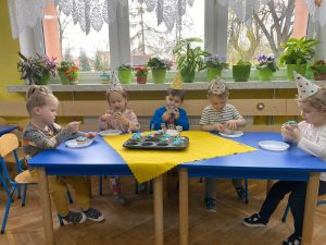 dzieci wraz z solenizantem  częstują się słodkimi, urodzinowymi mufinkami 