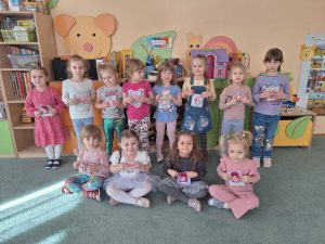 Dziewczynki z grupy pozują do zdjecia. W rękach trzymają upominki z okazji dnia kobiet.