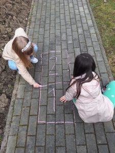 Dziewczynki malują kredą grę - klasy.