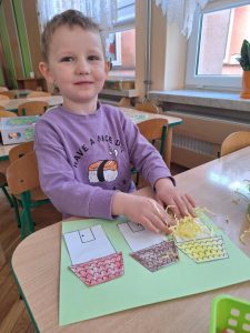 Chłopiec wykonuje prace plastyczną - domki dla trzech świnek.