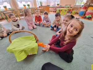 Dziewczynka trzyma zabawkową wiertarkę, którą wyjęła z kosza.