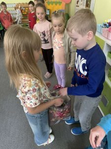 Chłopiec wyjmuje cukierka z prezentowej torby, którą trzyma solenizantka.