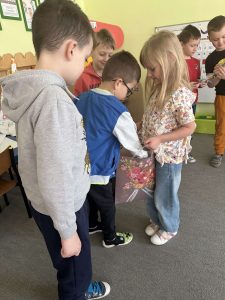 Chłopiec wyjmuje cukierka z prezentowej torby, którą trzyma solenizantka.