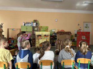 Dzieci oglądają spektakl pt Trzy świnki - w wykonaniu młodszych kolegów.