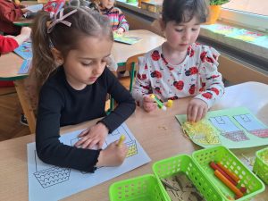 Dwie dziewczynki wykonują prace plastyczną - domki dla trzech świnek.