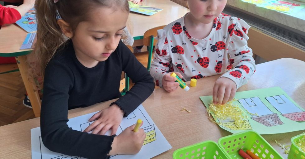 Dwie dziewczynki wykonują prace plastyczną - domki dla trzech świnek.