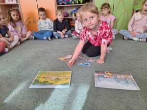 Dziewczynka klęczy na dywanie. dopasowuje ilustrację do odpowiedniego miejsca na dużym rysunku.
