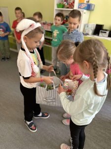Dwie dziewczynki częstują się słodyczami od kolegi, który ma urodziny.