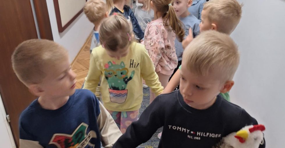 Grupa dzieci ustawiona w pary idzie korytarzem.