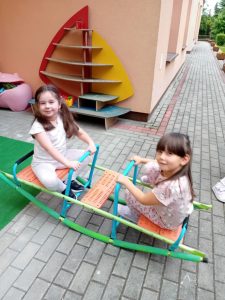 Dwie dziewczynki bujają się na huśtawce.
