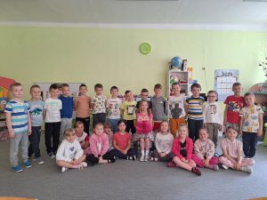 Solenizantka siedzi na środku. Wokół niej stoją dzieci z grupy.