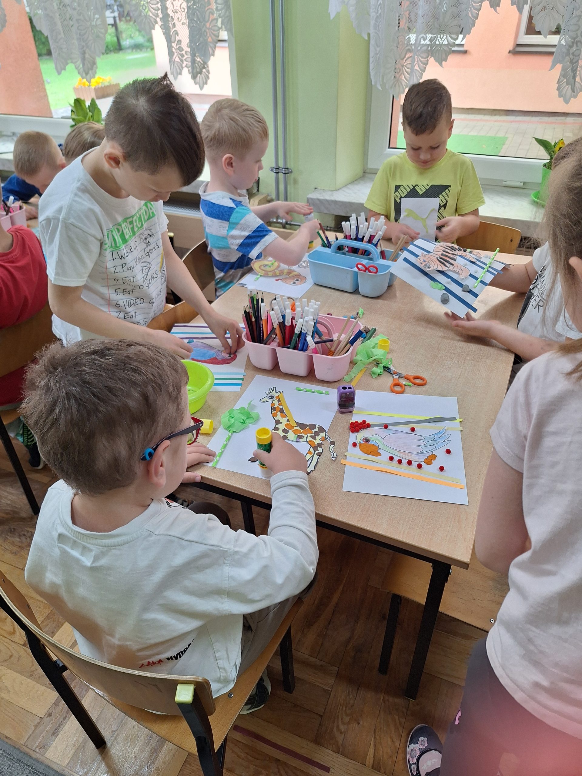 Dzieci wykonują pracę plastyczną. Według własnego pomysłu ozdabiają zwierzęta egzotyczne.